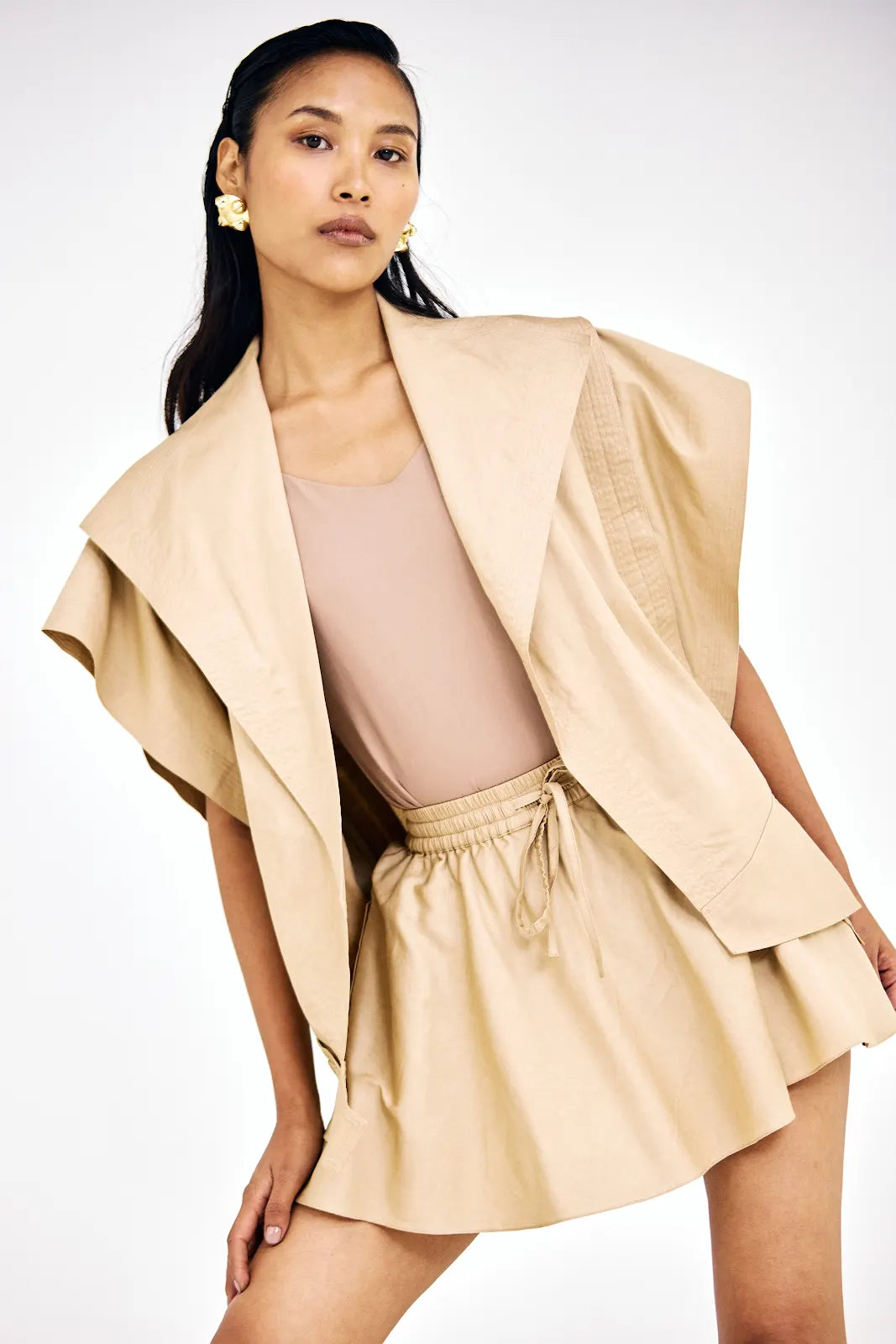 Asymmetrical beige jacket paired with matching cotton twill mini skirt